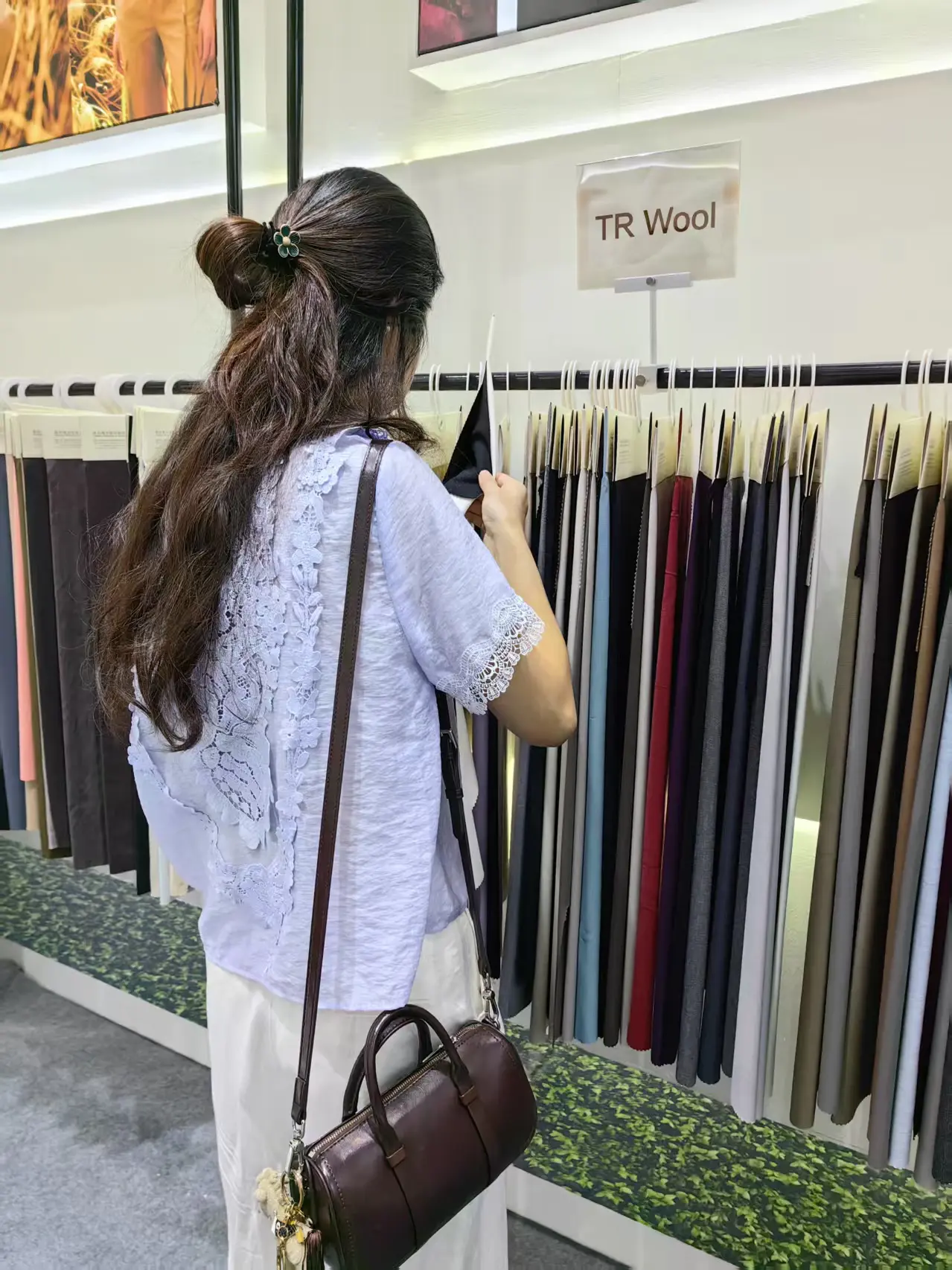 Visitor browsing fabric rolls at the 푸싱 텍스타일 booth